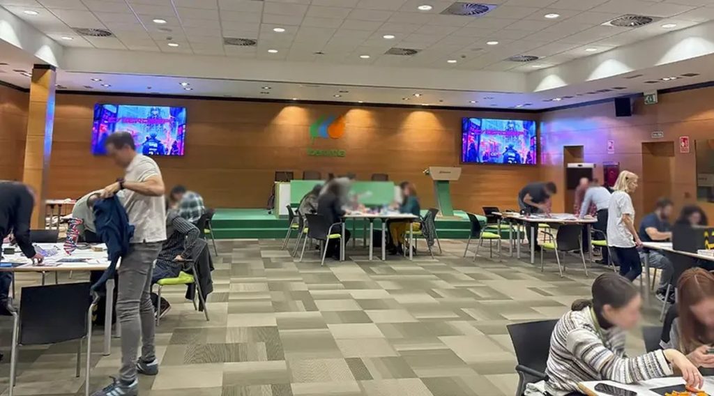 Escape room para empresas: salón de hotel con una mesa por equipo y pantallas durante un escape room para empresas