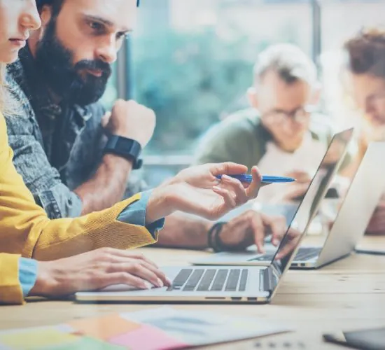 Compañeros de trabajo colaboran con portátiles en una mesa durante una sesión de team building online