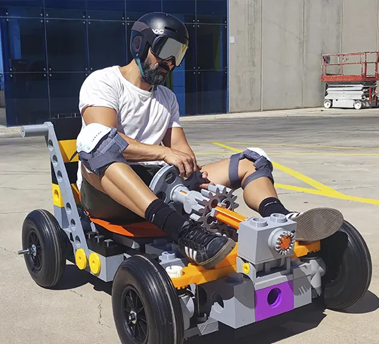 Participante con casco conduce un coche construido con bloques gigantes de tamaño real