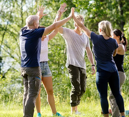 Equipo celebra chocando las manos en círculo al aire libre, dinámica para fortalecer la cohesión