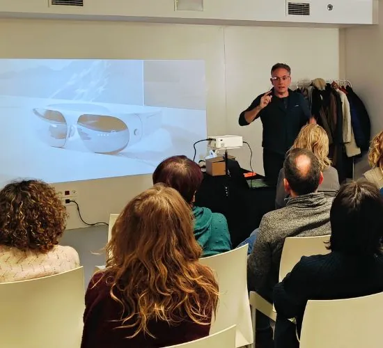 Ponente presentando unas gafas de realidad mixta proyectadas en pantalla ante el público