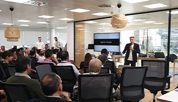 Formación para empresas en una oficina: ponente frente a un auditorio lleno de empleados