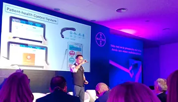 Ponente explicando un sistema digital de control de salud ante el público de un auditorio