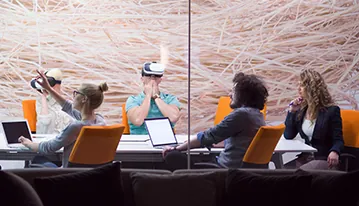 Compañeros de trabajo probando gafas de realidad virtual en una sala de reuniones acristalada