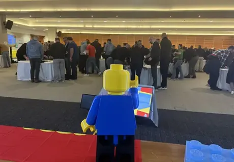 Figura gigante de Lego ante una sala llena de participantes