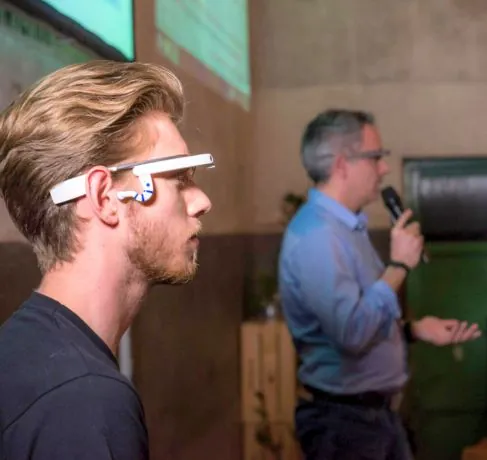 Asistente con gafas inteligentes mientras un ponente habla con micrófono en un evento
